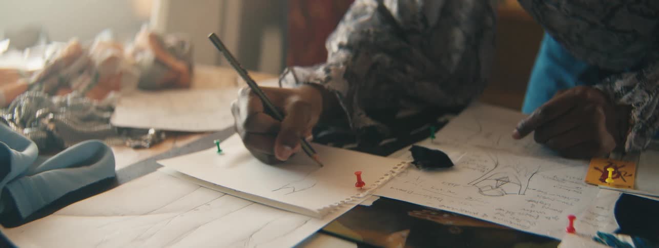 Hands of a woman drawing on a white sheet of paper on the table