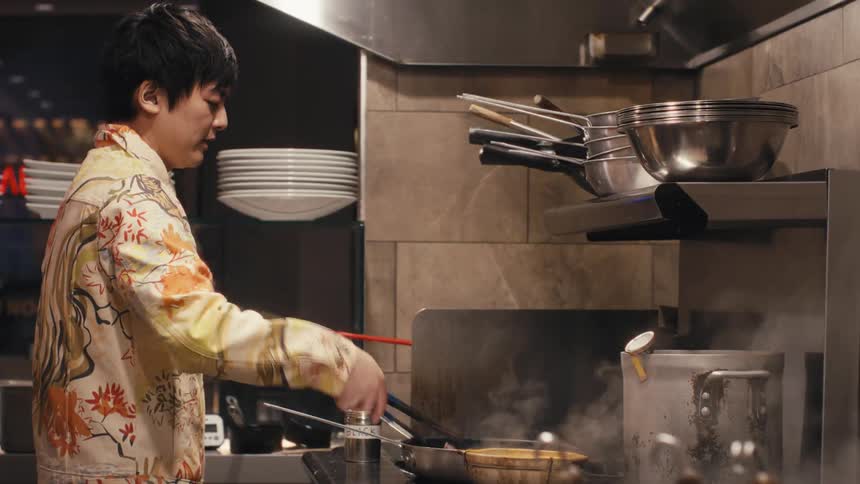 Chef in a restaurant kitchen preparing food in a frying pan