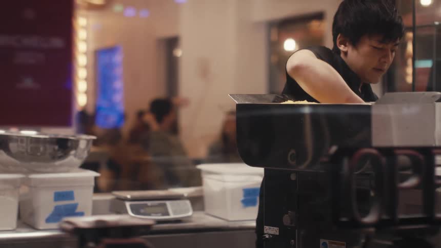 A restaurant worker makes food behind a glass window