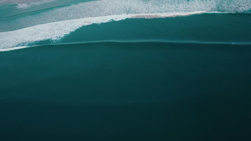 Aerial view of the ocean with several foamy waves