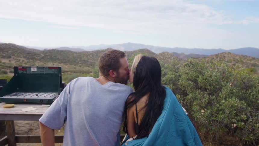 Couple sitting in a room with a mountain view kissing