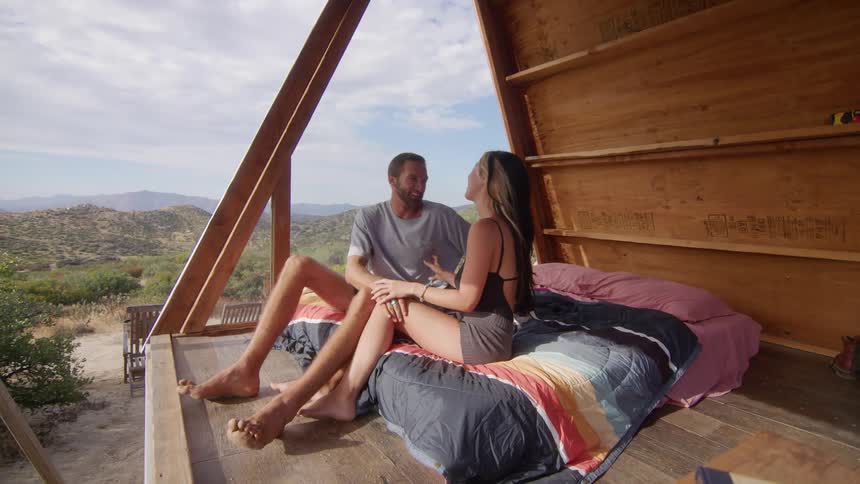 Man and woman sitting on the bed of a cabin having romantic contact