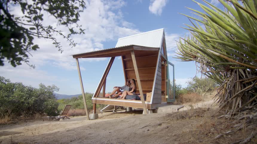 Couple of a man and a woman sitting in a hut on a hill surrounded by undergrowth