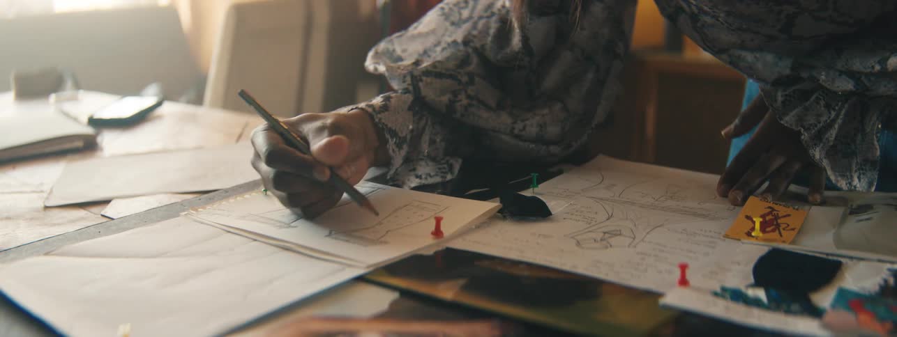 Closeup of a designers hand carefully drawing miniature dress sketches