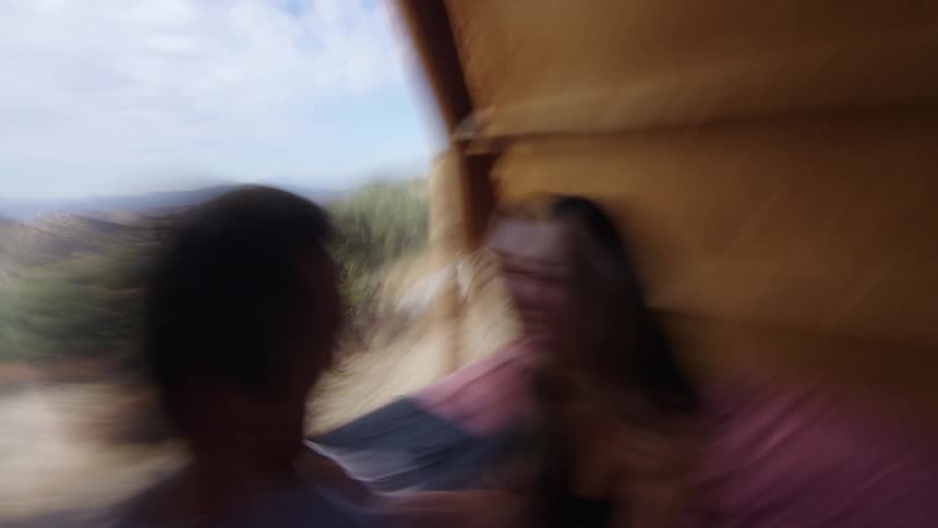 A man and woman cuddle on a bed in a small shelter