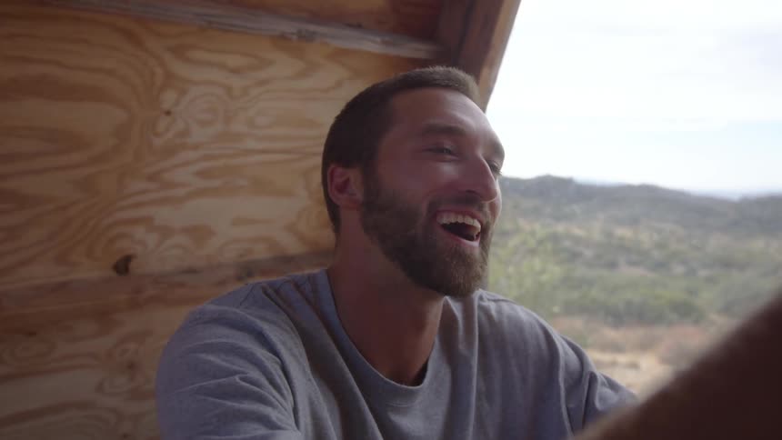 Man sitting in a camping cabin interacting with another person