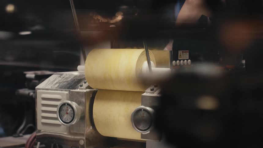 Person operating a pasta machine in a restaurant kitchen