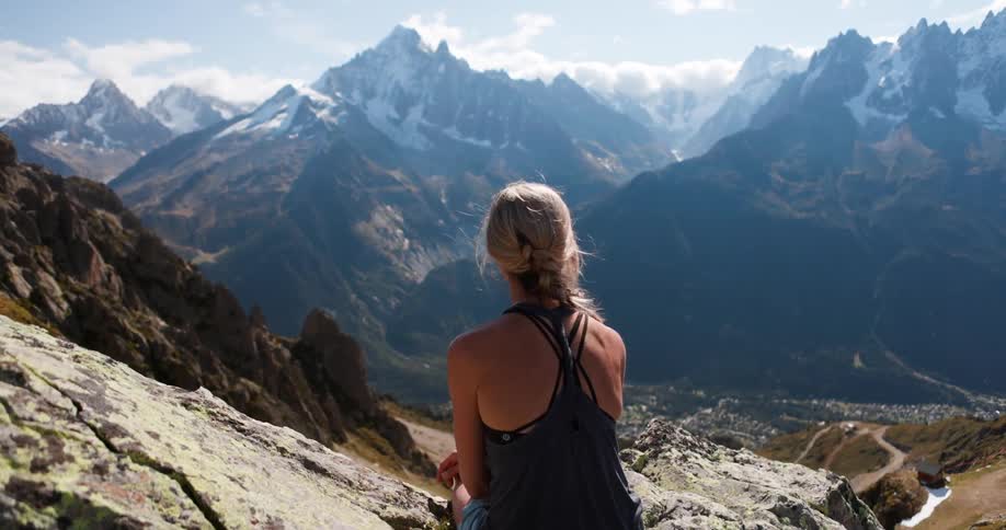 Woman sitting on rocks of a mountain on a cliff with stunning scenery