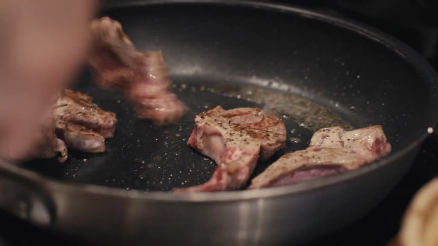 Hand cooking meat in a frying pan and a soup next to it