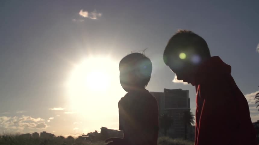Two kids standing in a field on a sunny day