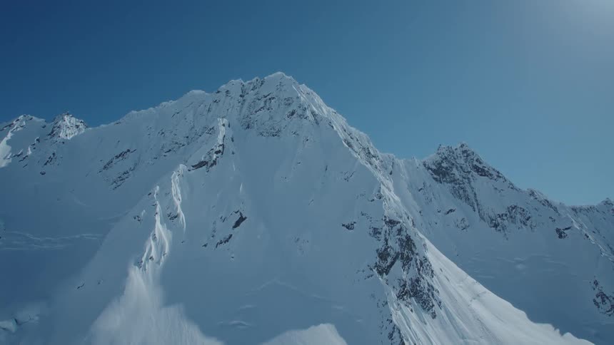 Aerial panorama of snowcapped mountain range on a clear blue sky day