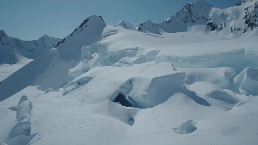 A region with a lot of dense snow on the ground and mountains behind