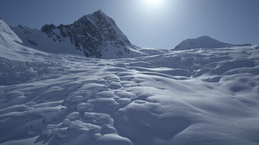 The sun is reflecting on the snow on the mountain