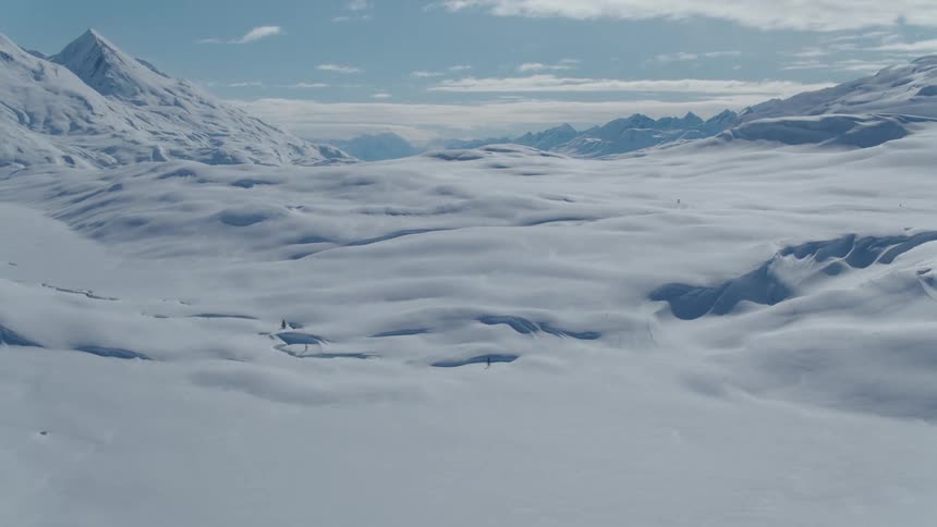 Snow covers the valley between mountains on a cloudy winter day