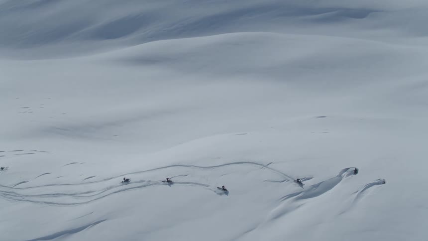 Four people using snowmobiles on a snowcovered plain