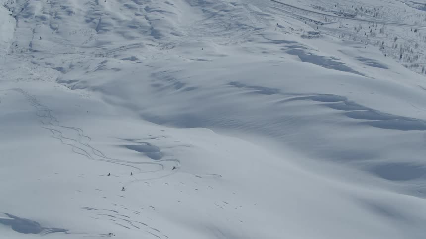 Group of people with snowmobiles climbing mountains covered by snow