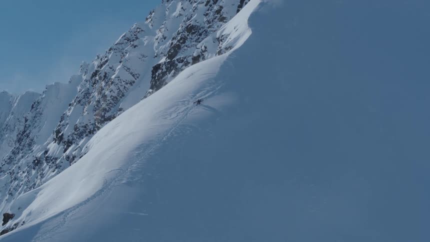 Someone walking up the ridge of a snow covered mountain carrying a snowboard
