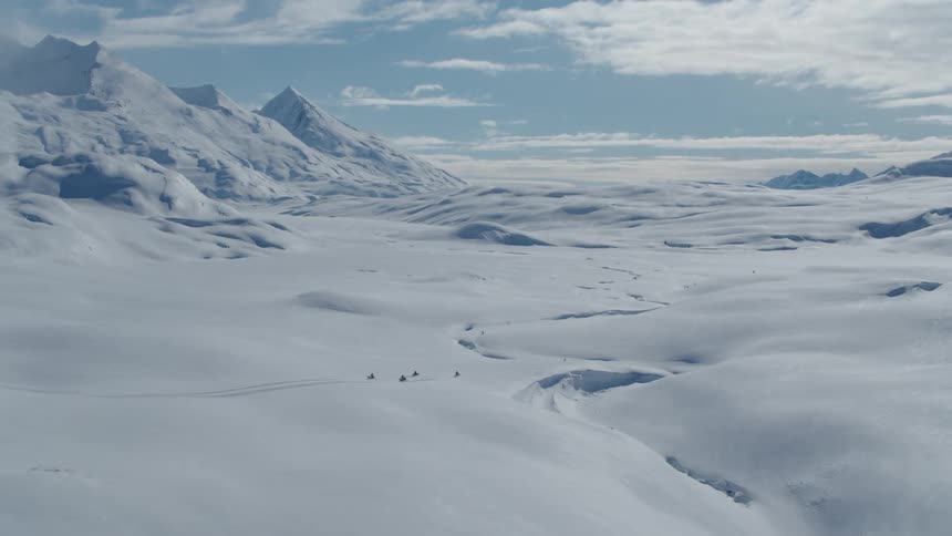 People are riding their snowmobiles through the arctic
