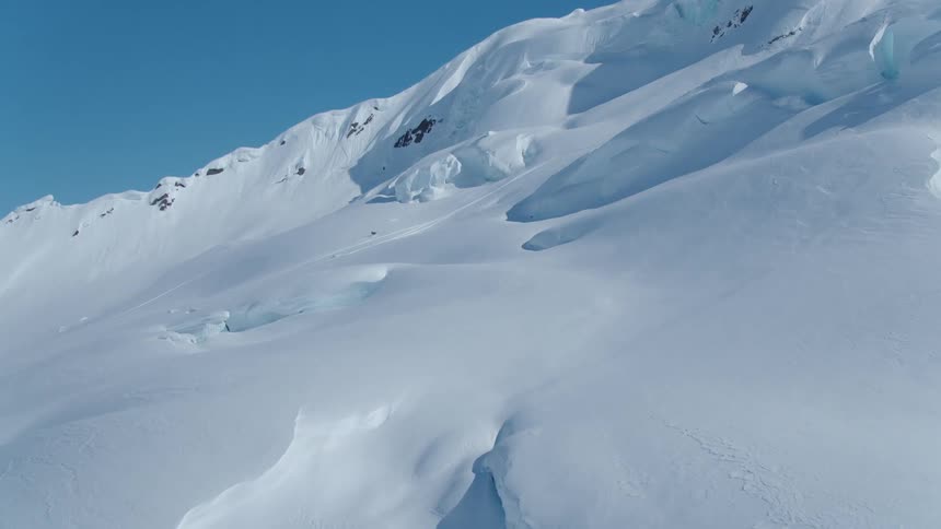 A person in a snowmobile going up a snow covered mountain