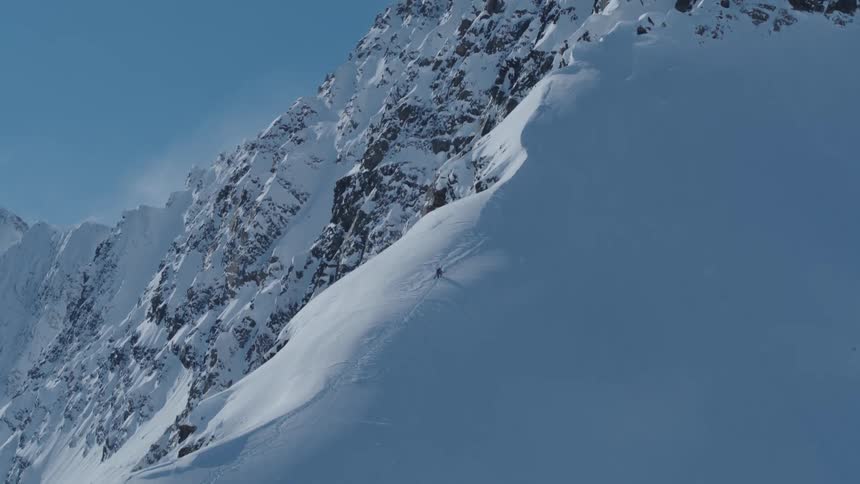 Aerial view of a person climbing a large snow covered mountain