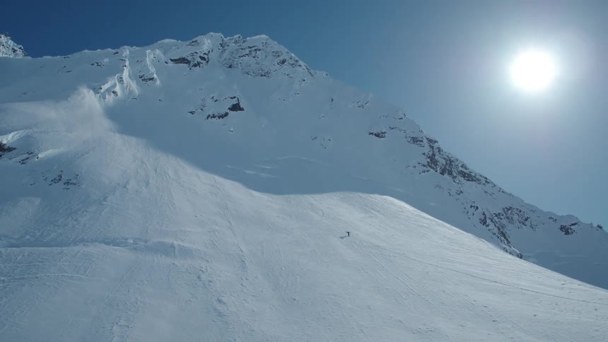 Person climbing a large snowy mountain with the sun above