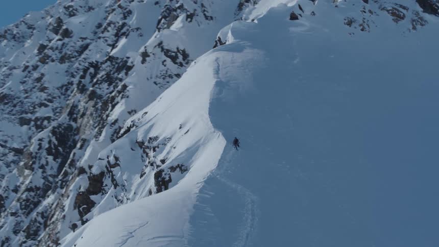 Person climbing a steep mountain covered in snow
