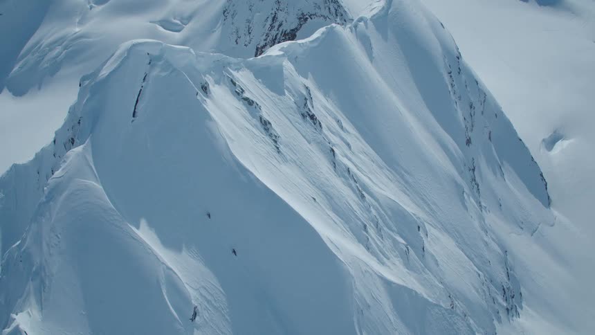 An aerial view of a huge mountain that is completely covered in snow