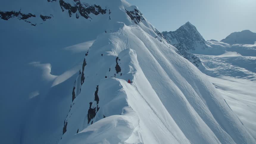 A skier navigating a narrow ridge on a snowcovered mountain peak
