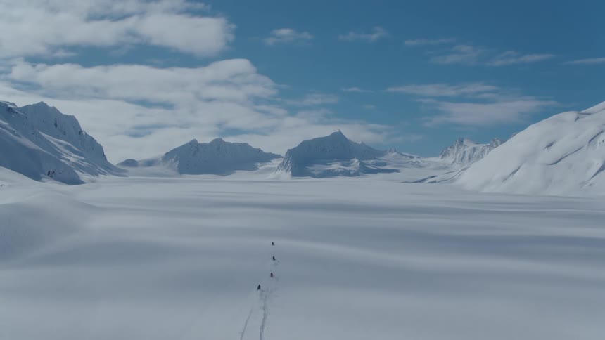 Aerial of people snowmobiling in the back country on a bluebird day