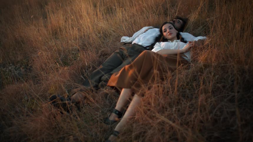 Man and woman lying together embracing in a field