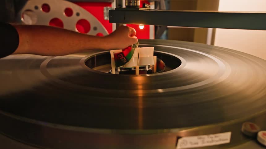 Persons hand adjusting a film strip on a vintage piece of equipment
