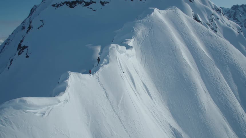 Aerial view of a person on the peak of a snowy cliff