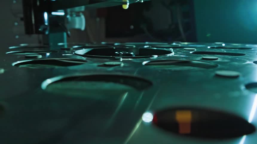 A flat metal plate with several circular cutouts on its surface