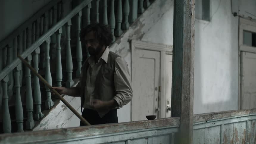 Man in classic suit smoking and walking holding a squeegee