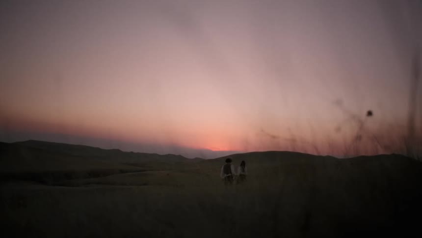 Couple holding hands walking towards the sunset in the desert