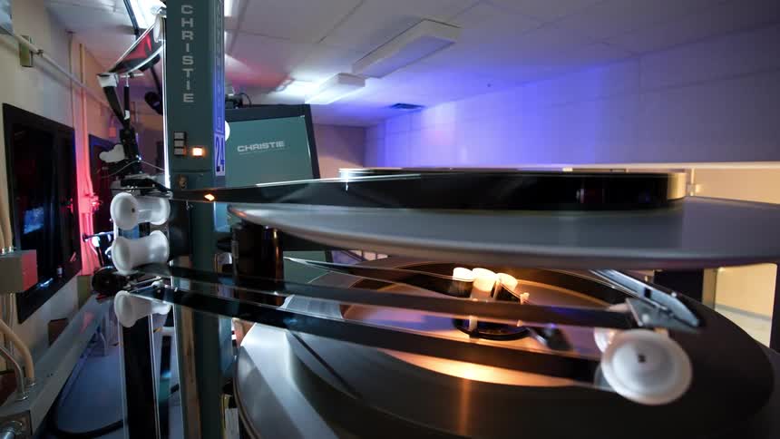 The film reel spins on the projector wheels