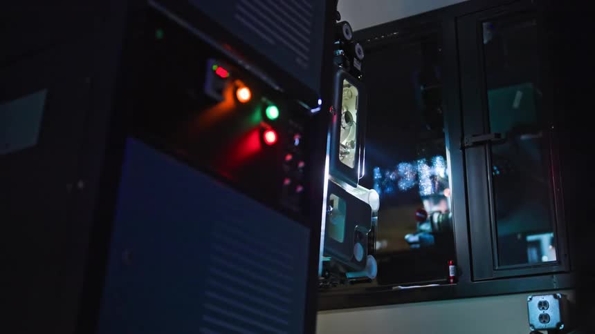A computer hardware with some green and red lights and next to a window that is reflecting some ambient lights