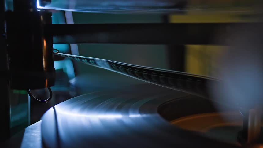Close up of a strip of film winding through a film projector and onto a reel