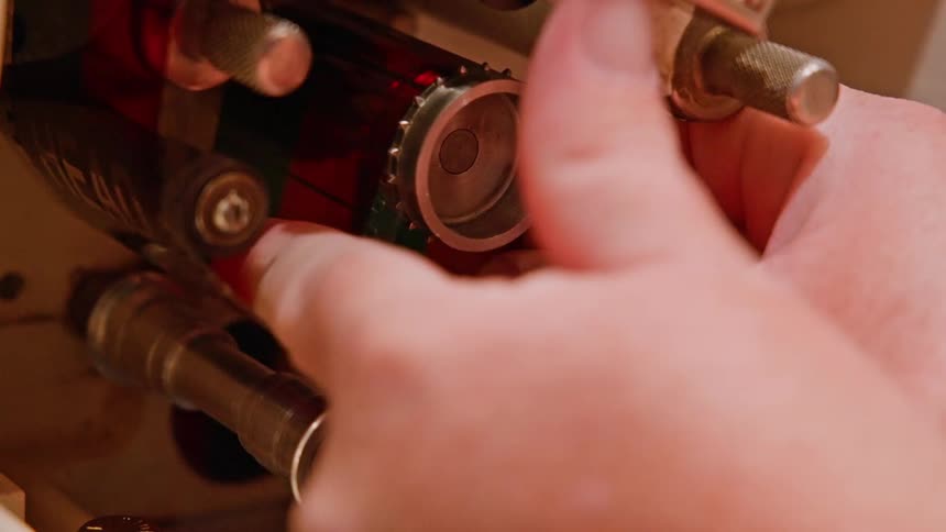 Hand adjusting a film strip on a retro equipment
