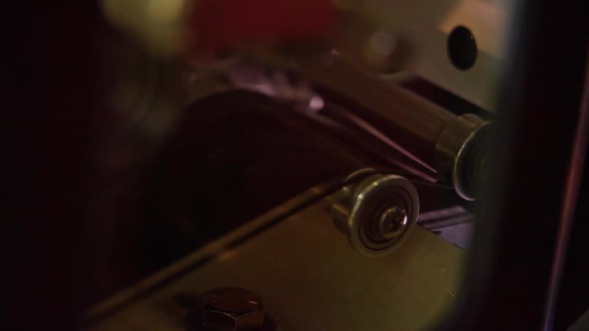 Close up of a machine with metal devices playing a retro movie from a tape