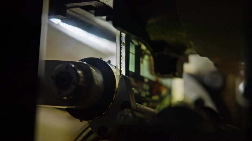 A closeup of a film reel being processed by a machine