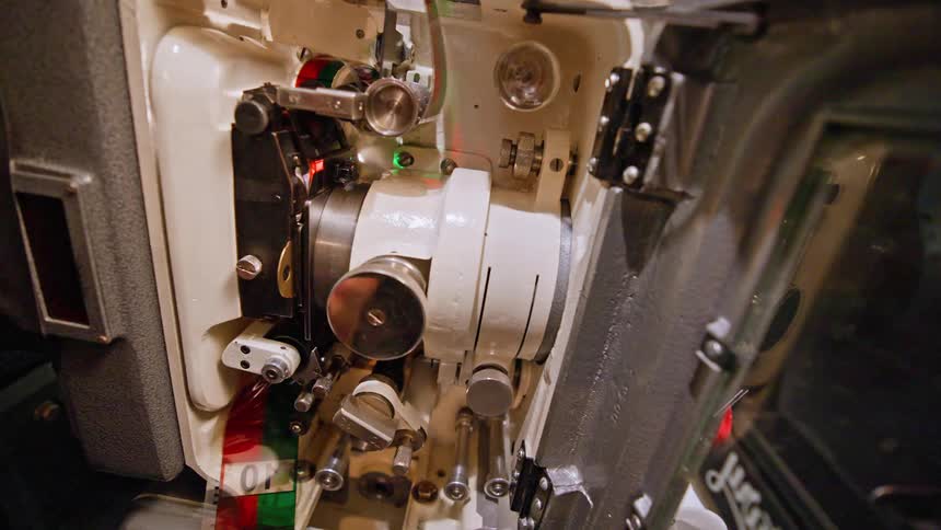 Pair of hands setting up a retro machinery with a film strip
