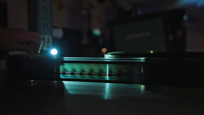 A person helps guide a roll of film as it is spooled by a machine