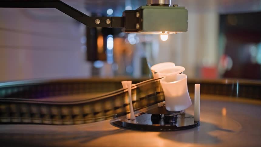 A film projector with a strip of film passing through it illuminated by a bright light