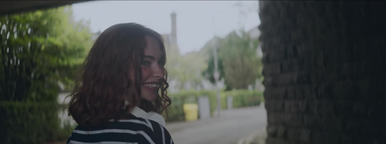 Red curly haired woman walking and looking back smiling