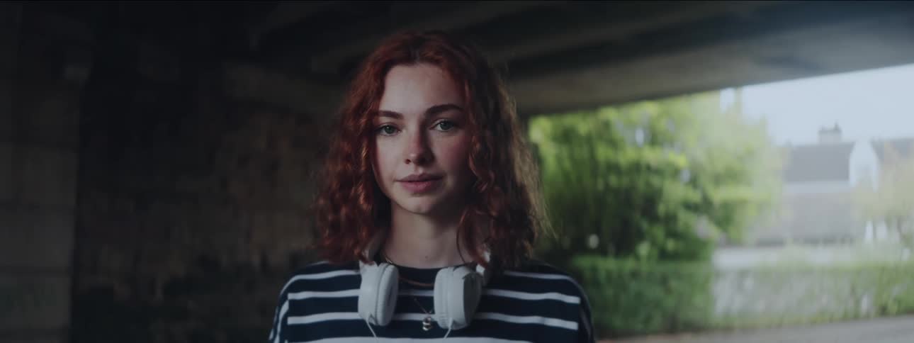 Red curly haired woman with white headphones around her neck