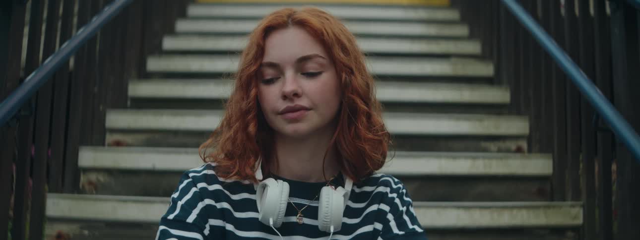 Young redhaired woman sitting on the stairs in an openair environment