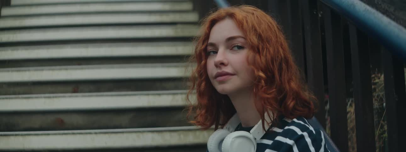 A clip of a redhead lady sitting on a staircase