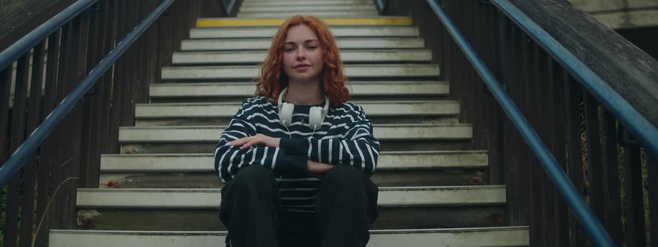 Redhead woman sitting on stairs with arms crossed