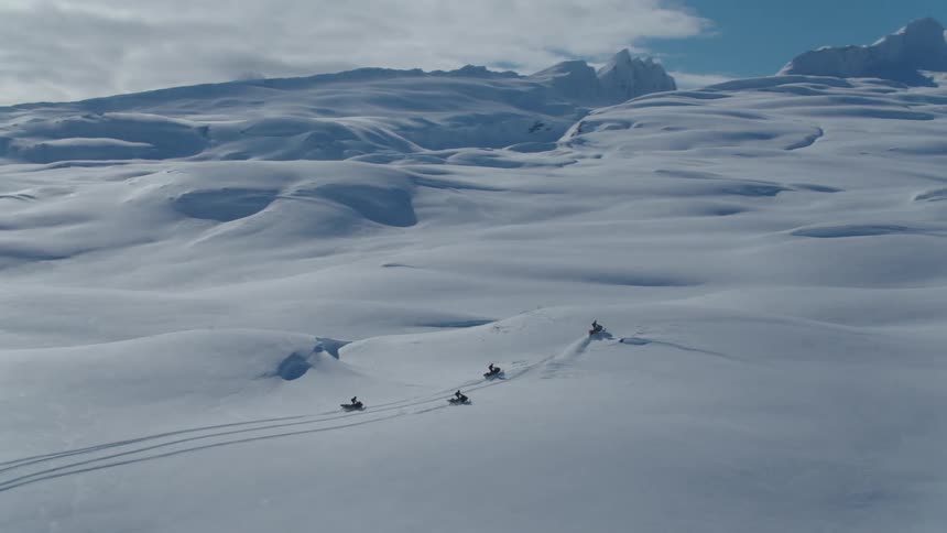 Some people riding snowmobiles in a completely covered area